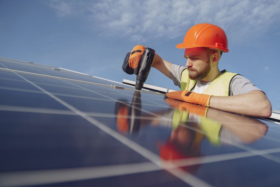 Smiling professional solar panel installer reviewing site plans